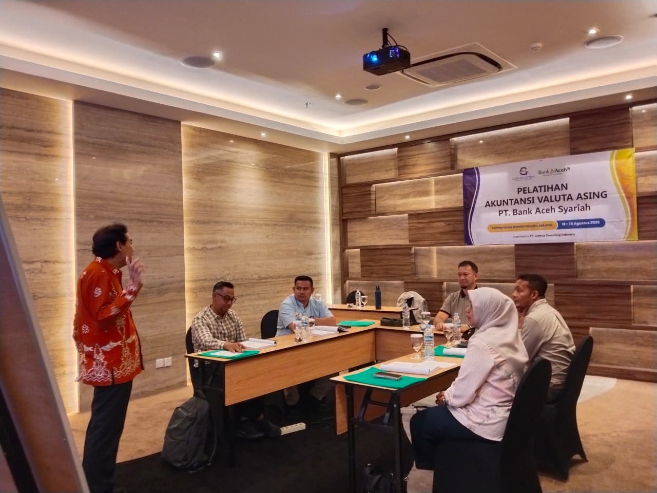 Sesi pelatihan akuntansi valuta asing dengan peserta di meja berformasi U